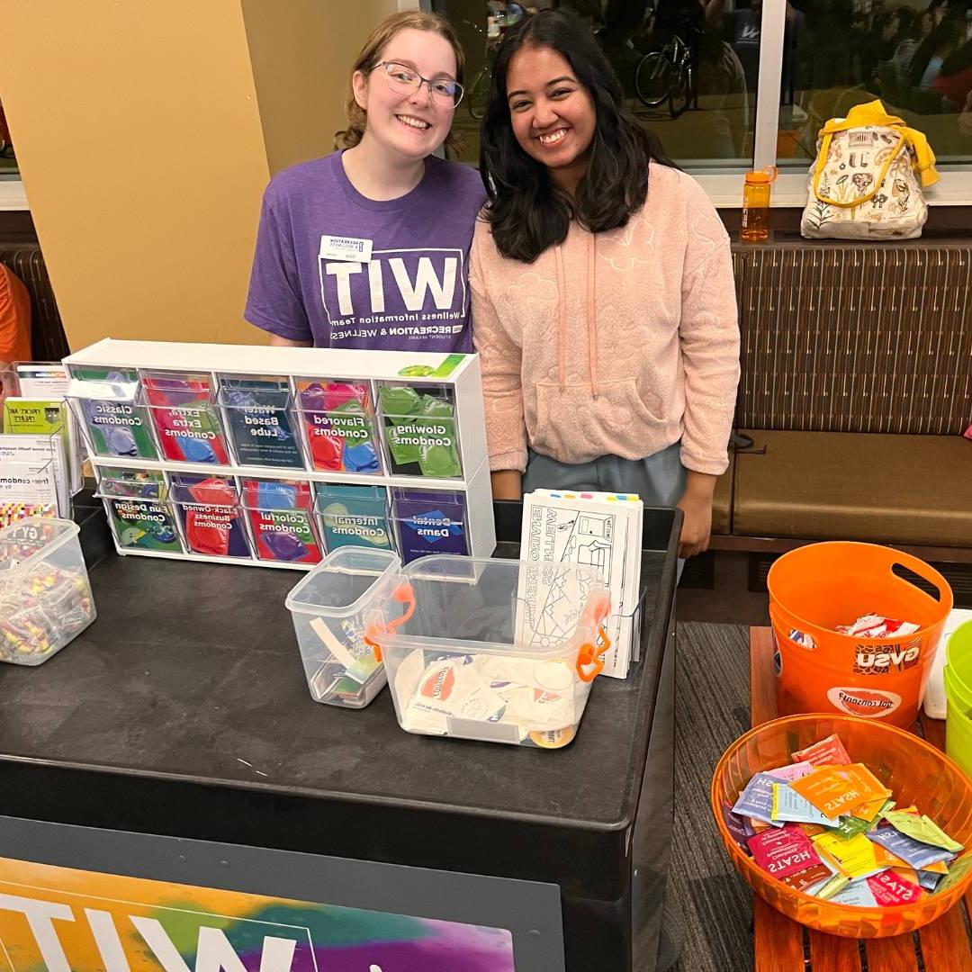 Two WIT peer educators behind the WIT cart